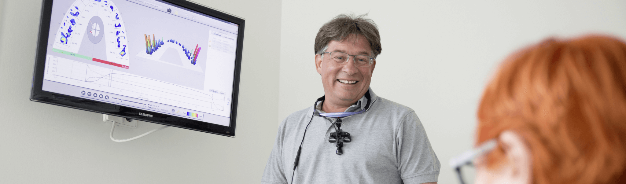 Prophylaxe - Dr. Rentschler lachen mit Patientin im Gespräch, dahinter ein Bildschirm